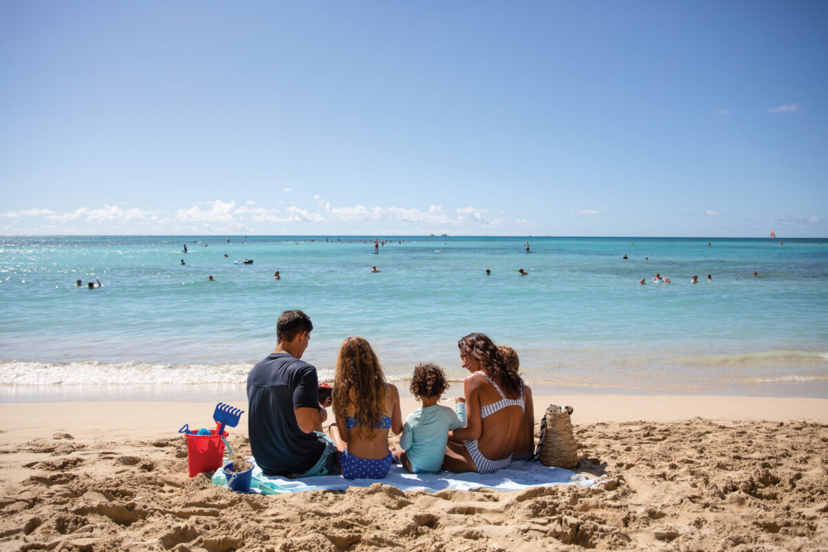 Family sitting on the beach in front of the ocean.