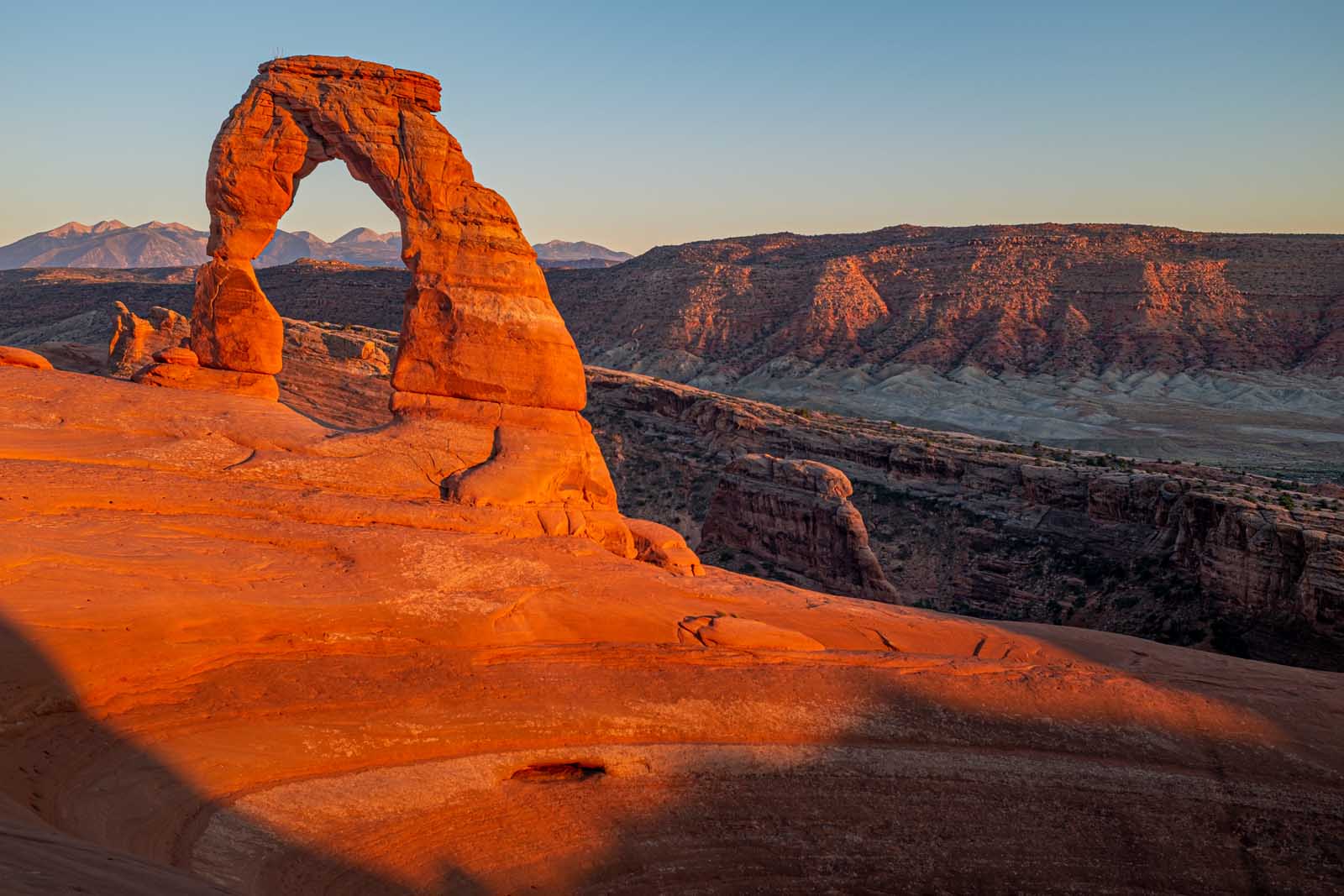 The famous Delicate Arch standing against a sunset sky, one of Utah's most beautiful national parks.