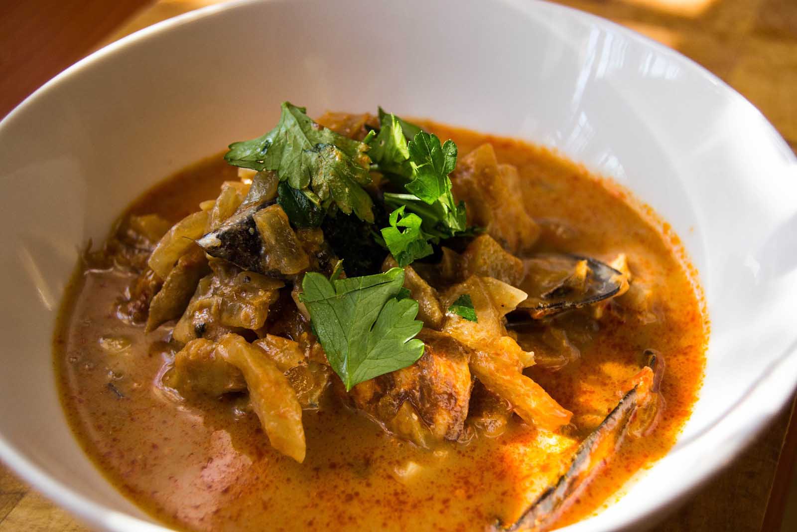 A bowl of traditional French Bouillabaisse, a saffron-infused fish stew served with croutons and rouille.