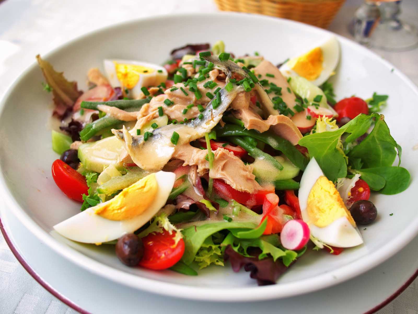A composed Salade Niçoise, a classic French dish with tuna, green beans, tomatoes, olives, and egg.